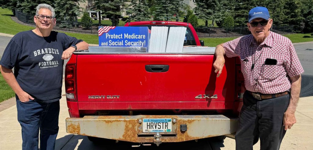 Two Patriotic Chickens standing beside a red pickup full of yard signs.